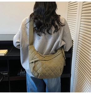 Detail of olive green quilted dumpling bag with wide strap worn on model's back