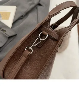 Detail of silver metal hook and textured brown lychee leather on bucket handbag