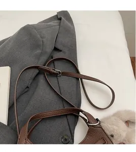 Detail of adjustable leather strap and cute rabbit pendant on a brown bucket bag