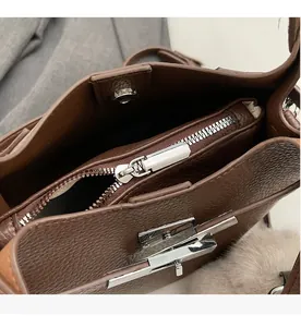 Macro view of smooth silver metal zipper and brown lychee grain leather on bucket bag