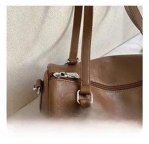 Détails de la fermeture éclair argentée et texture cuir du sac Boston marron