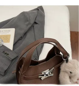 Detailed macro of brown lychee leather bucket bag with silver lock and cute bear charm