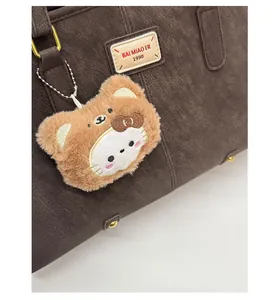Close-up of a brown plush bear charm with white embroidery detail on a vintage bag