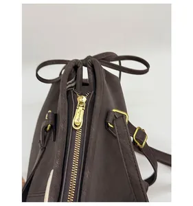 Close-up of golden zipper hardware with bow tie detail on a brown shoulder bag
