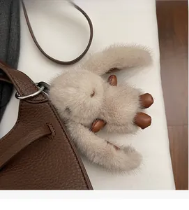Close-up of a plush bunny bag charm with faux fur and leather details on a leather bag