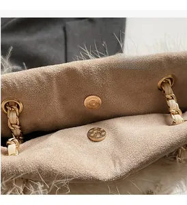 Close-up of golden magnetic buckle and chain strap on quilted tote bag with faux fur trim