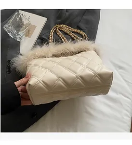 Close-up of beige quilted tote bag featuring plush feather trim and gold chain strap