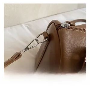 Détails des crochets en métal argenté et de la fermeture éclair du sac Boston en cuir brun