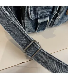 Detail of blue washed denim bag strap with vintage silver rectangular metal buckle
