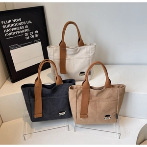 Trois sacs cabas en toile minimalistes en beige, gris et kaki avec broderie cartoon
