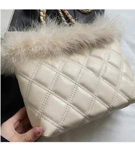 Detail view of quilted cream shoulder bag featuring elegant feather trim and gold chain strap