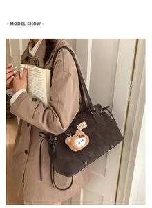 Brown faux leather tote bag with gold rivets and teddy bear charm shown on model