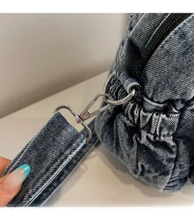 Detail of blue denim handbag featuring premium silver hardware and pleated fabric texture
