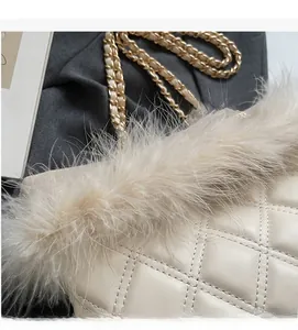 Detail of cream quilted tote bag featuring plush feather trim and gold chain strap