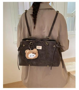 Back view of a vintage dark brown shoulder bag with plush bear charm on model