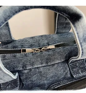 Detail of smooth silver metal double zippers on blue denim canvas large capacity handbag