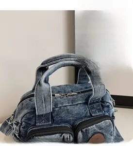 Detail of reinforced handles and durable metal zippers on a dark blue denim shoulder bag
