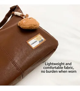 Detail of dark brown tote bag featuring pebbled faux leather and plush bear charm