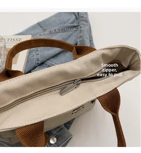 Détail de la fermeture éclair en métal lisse sur le grand sac cabas en toile beige et marron