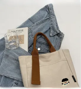 Détail du sac cabas en toile crème avec anses brunes et broderie de dessin animé
