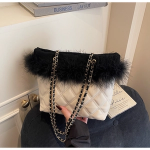 Detailed shot of quilted white leather bag with black feather trim and golden chain strap