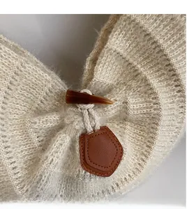 Detailed macro view of durable horn buttons and leather trim on knit tote bag