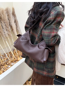 Brown pleated shoulder bag with vertical texture and side flap pocket in autumn setting