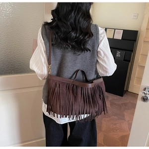 Détail d'un sac bandoulière en daim marron avec franges et finitions dorées chic
