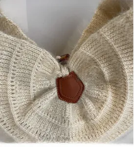 Detailed macro view of beige knit tote bag with thick texture and leather patch
