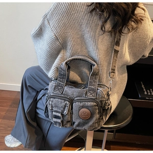 Detailed back view of a dark gray washed denim crossbody bag worn in a lifestyle setting