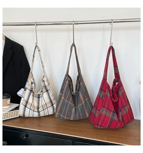 Three oversized plaid tote bags in various colors displayed on a modern metal rack