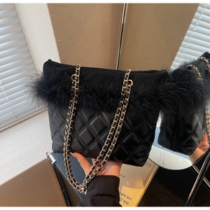 Detail of black quilted shoulder bag with feather trim and gold chain strap