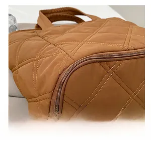 Close-up of the durable quilted nylon bottom and metal zipper on the brown tote bag