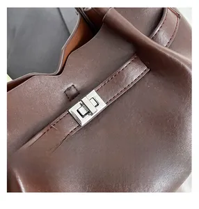 Detailed close-up of dark brown leather bag with silver metallic twist lock and stitching