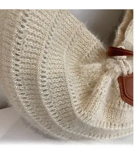 Close-up of beige knit tote bag texture with brown horn button and leather trim detail