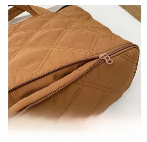 Detail of smooth zipper closure on brown quilted tote bag with diamond pattern