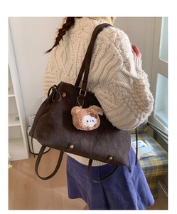 Detail of dark coffee tote bag with teddy bear pendant worn over a white sweater