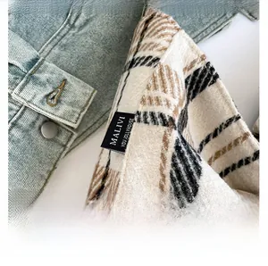 Close-up of Malivi brand tag on heavy-textured black and brown plaid woven tote bag fabric