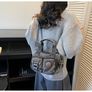 Detail of washed denim shoulder bag with dual zipper pockets and vintage hardware
