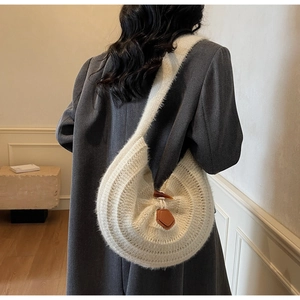 Detail of cream knit shoulder bag featuring a wood horn buckle and plush woven texture