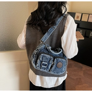 Detail of vintage washed blue denim crossbody bag with utility pockets and metal buckle
