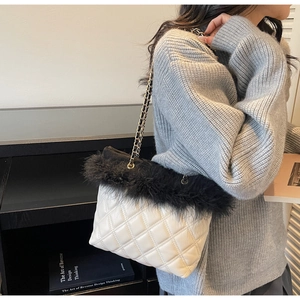 Close-up of quilted white leather bag with black faux fur trim and gold chain strap