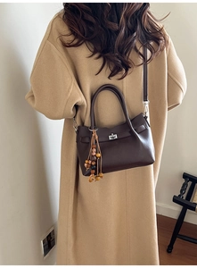 Detailed view of deep brown leather bucket bag with silver twist lock and ethnic beaded charm