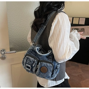Detail view of denim crossbody bag with dual zipper pockets and washed blue texture