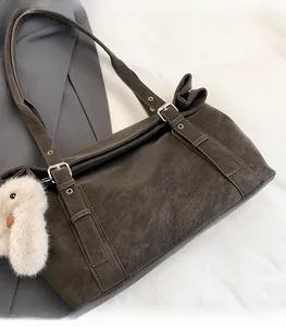 Detail of matte charcoal shoulder bag featuring silver buckle and white plush bird charm