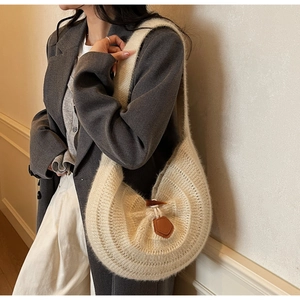 Vue détaillée du sac hobo en maille crème avec bouton en corne et détail en cuir
