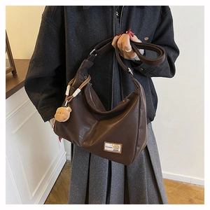 Close-up of brown PU leather tote with a cute bear pendant and fashion patch detail