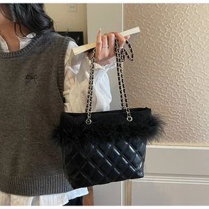 Dettaglio borsa in pelle trapuntata nera con elegante bordo in piume e catena dorata