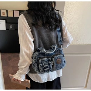 Detail of blue denim crossbody bag featuring multiple pockets and a round leather logo