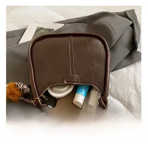 Dettaglio dell'interno capiente di una borsa vintage in pelle marrone con accessori